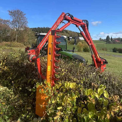 Trjáklippur á armi á dráttarvél að klippa gróður við stíg